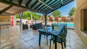 An outdoor patio with a covered seating area, a pool, and a barbecue setup. - Spacious 410m² 3-star cottage: private heated pool, spa, canoes and paddl (Trentels)