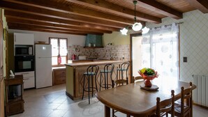 A kitchen with wooden beams, a dining table with chairs, a microwave, a refrigerator, and a window with curtains. - Spacious 410m² 3-star cottage: private heated pool, spa, canoes and paddl (Trentels)