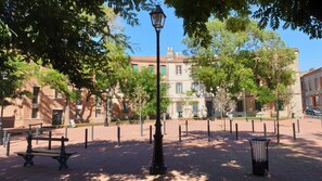 Une place pavée avec un banc, un lampadaire et une poubelle.
