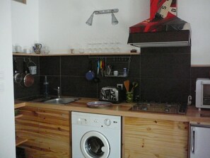 Eine kleine Küche mit Waschmaschine, Toaster und Mikrowelle.