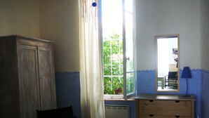 A room with a wooden cabinet, a chair, a dresser, and a window with curtains.