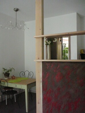 A dining area with a white table, two chairs, a potted plant, and a decorative vase.