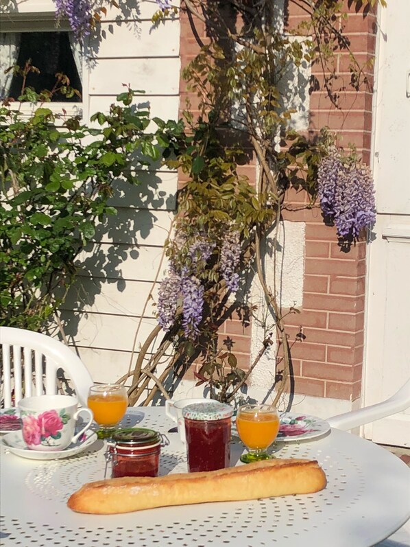 A table with a baguette, two cups of orange juice, and two jars of jam.