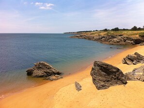 Ein Strand mit klarem Wasser, sandigem Ufer und Felsformationen.