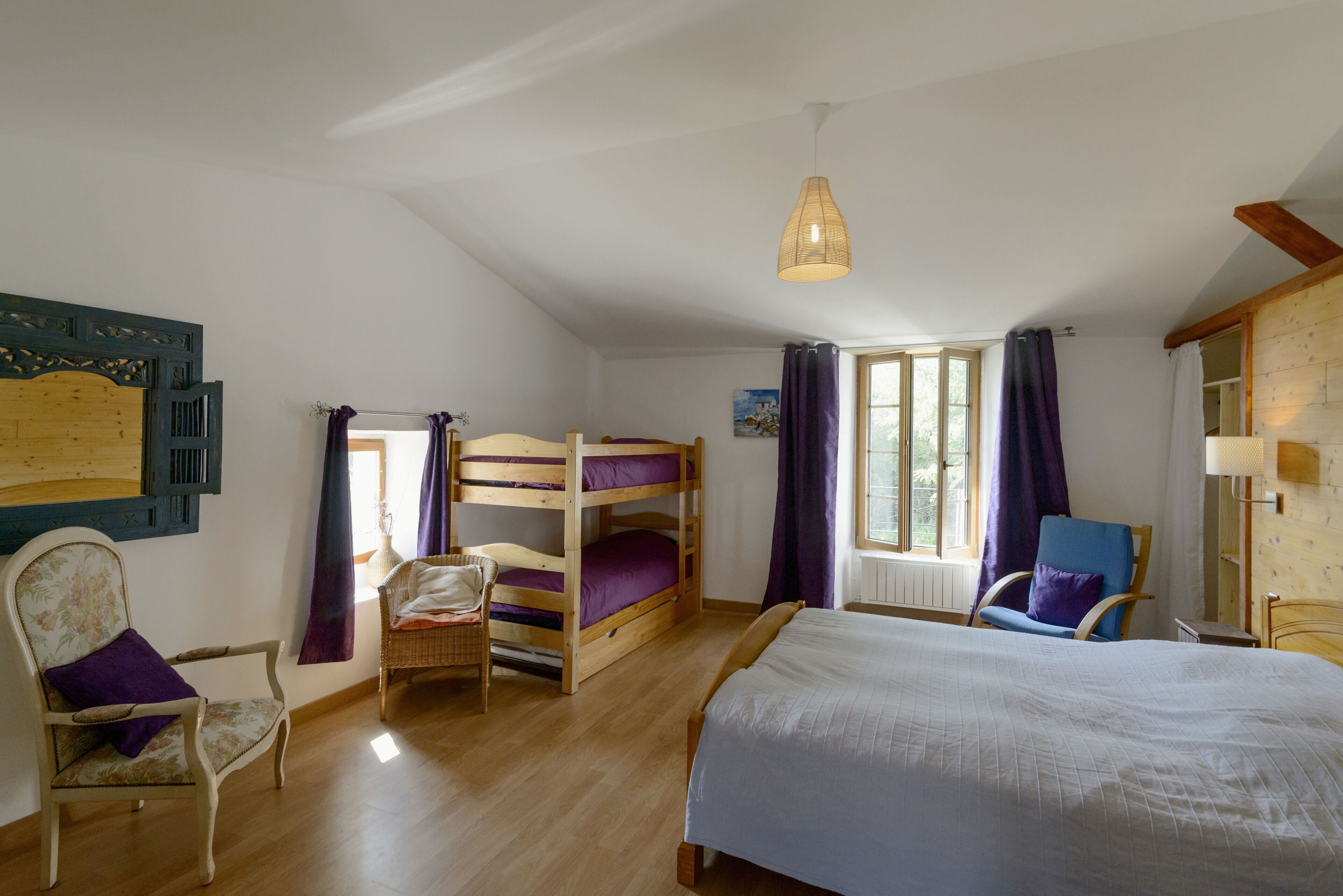 Una habitación con literas, una silla, un escritorio y una ventana con cortinas.