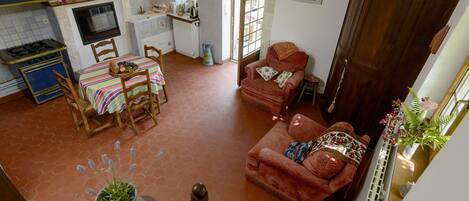 A spacious living area with a dining table, a sofa, and a kitchen in the background.