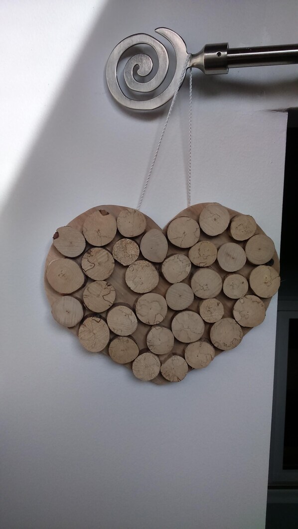 A wall decoration made of circular wooden pieces arranged in a heart shape.