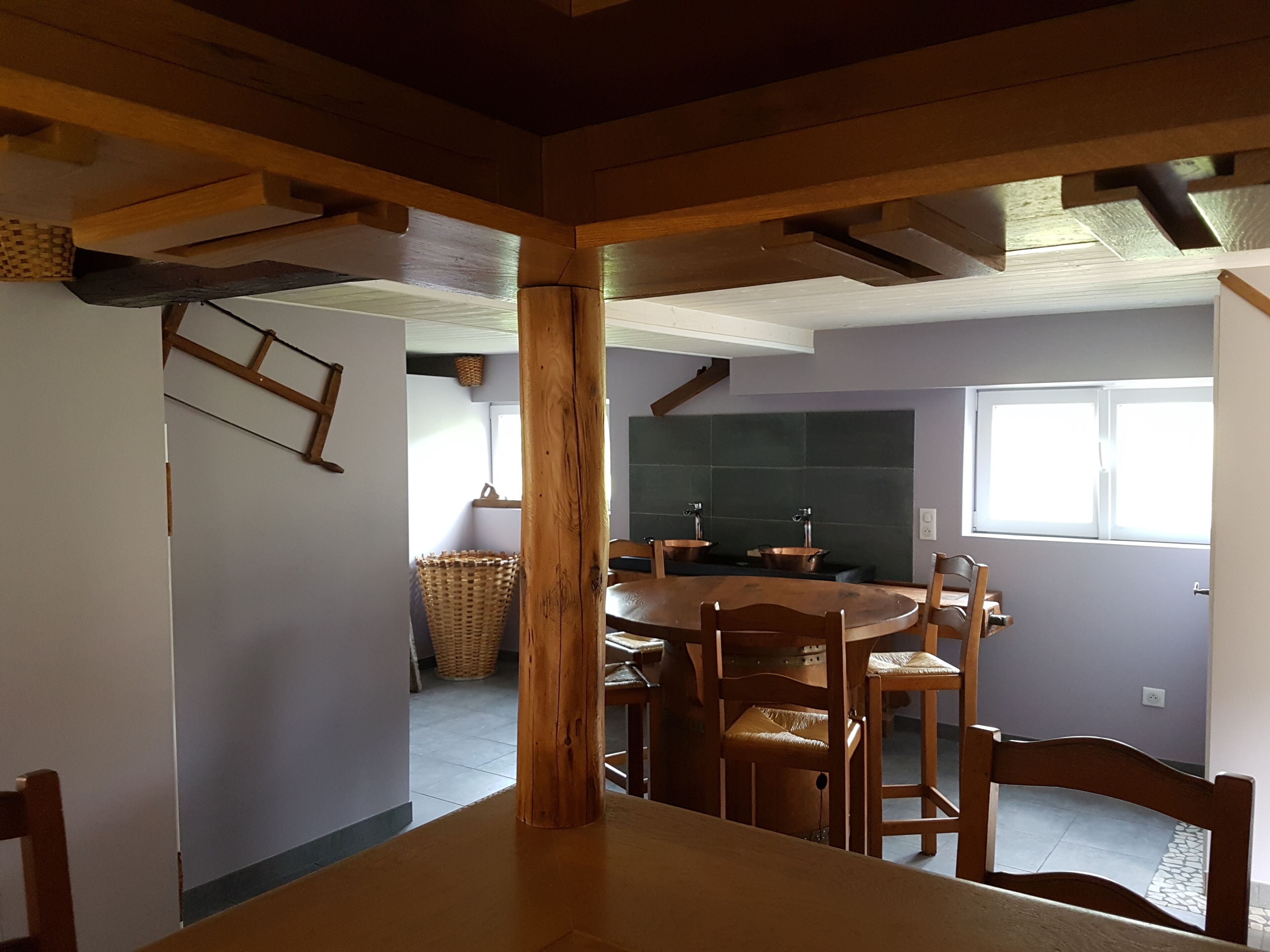 Ein Essbereich mit Holztisch und -stühlen, eine Küche mit Kupferwaschbecken und ein Fenster, das für natürliches Licht sorgt.