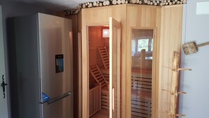 Ein Holzinnenraum mit einem modernen Kühlschrank, einer Holztreppe und einem an der Wand befestigten Kleiderhaken.