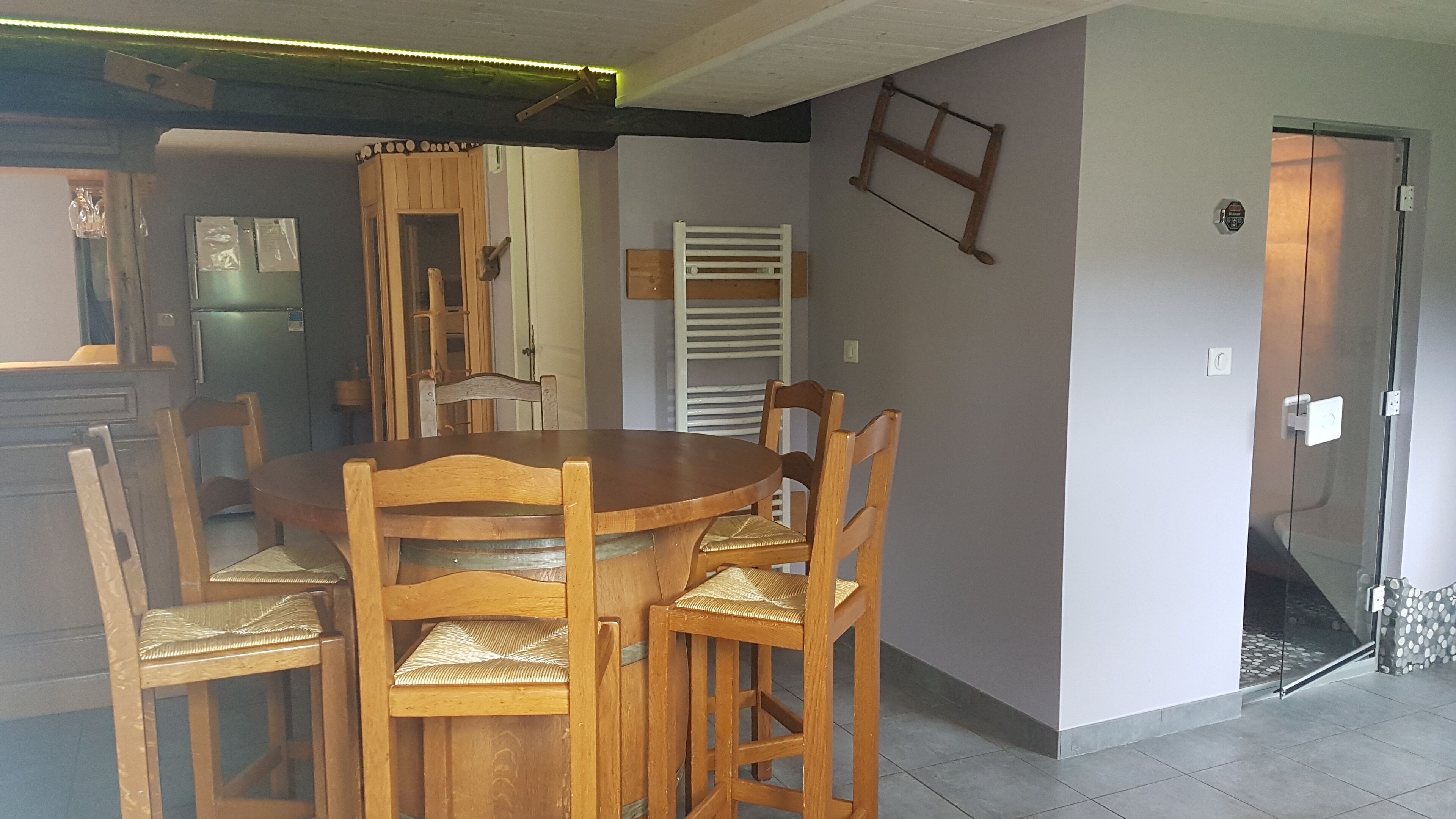 A dining area with a wooden table and chairs, a white radiator, and a glass door leading to a balcony.