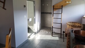 Ein Zimmer mit einer Holzleiter, einem gewebten Korb und einer Metallschaüssel auf einem Tisch.