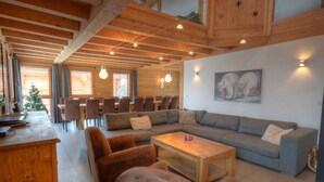 A cozy living room with a wooden ceiling, a grey sofa, brown armchairs, a wooden coffee table, and a Christmas tree. - Grand Massif 8 bedrooms/8 bathrooms sauna, pool table, walk to village & gondola (Morillon)