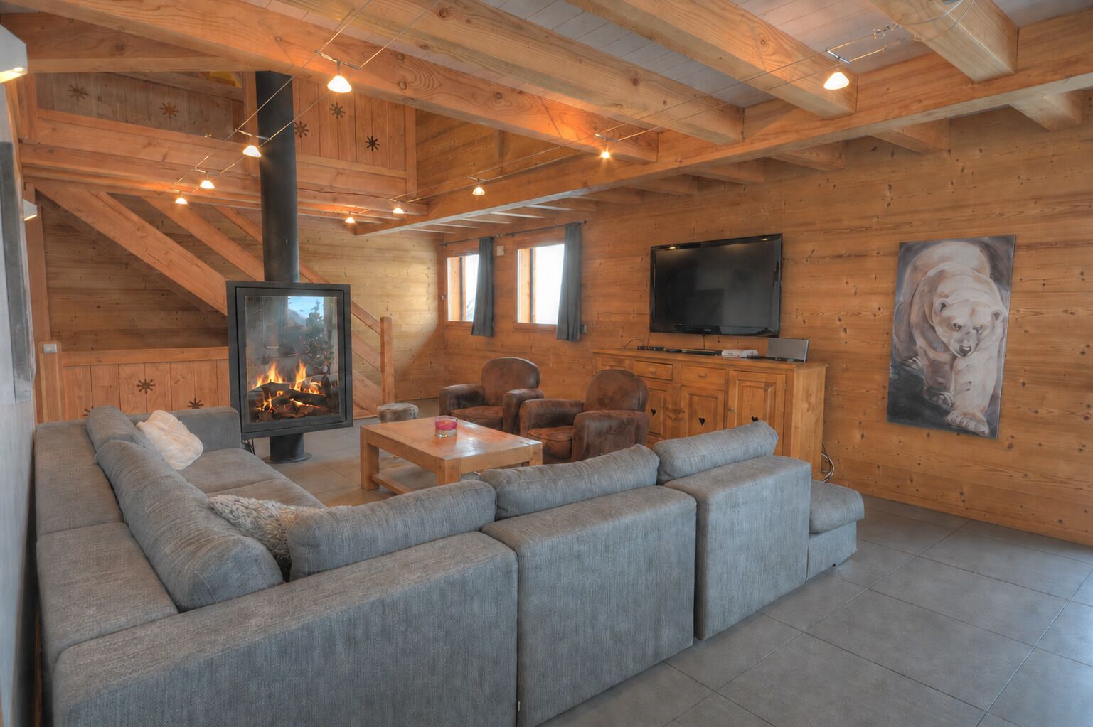 A cozy living room with a fireplace, a television, and a large sofa.