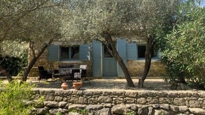A stone building with a patio area, outdoor seating, and olive trees.