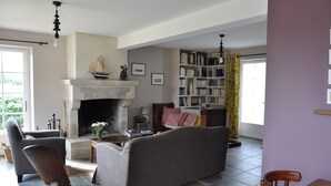 Un salon avec une cheminée, une bibliothèque et un coin repas.