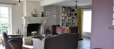 A living room with a fireplace, a bookshelf, and a dining area.