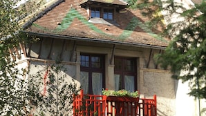 Il s’agit d’un bâtiment traditionnel, doté d’un toit en pente, de cadres de fenêtres en bois et d’une clôture en bois rouge qui se trouve au premier plan.