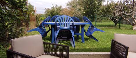 Ein Patio mit Korbmöbeln, einem blauen Plastiktisch und Stühlen.