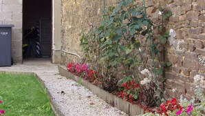 Un espace jardin aménagé avec un chemin de gravier, des plantes à fleurs et un mur en pierre.