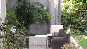 Une terrasse avec des meubles en osier, une table blanche et un mur en béton.