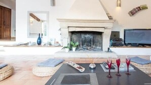 A spacious living area with a fireplace, a television, and a dining table set with wine glasses. - Starry EDEN (Saint-Paul-De-Vence)