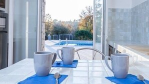 A modern kitchen with a glass door leading to a pool area. - Starry EDEN (Saint-Paul-De-Vence)