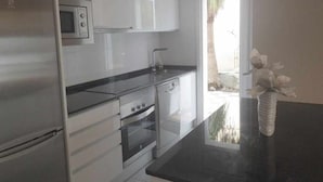 A modern kitchen with stainless steel appliances, a microwave, and a sink. - Ground floor with large terrace Beach at 350m Center and Port at 15mn by foot (Cambrils)