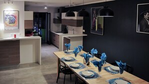 A modern dining area with a long table set for six, featuring blue napkins and plates. - Villa with 2 private pools - close to the beach (Bompas)
