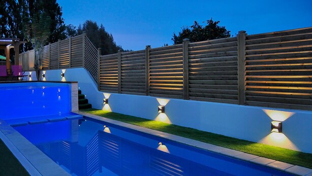 A swimming pool with a wooden fence and built-in lighting, surrounded by a well-maintained lawn. - Villa with 2 private pools - close to the beach (Bompas)