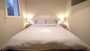 Ein ordentlich gemachtes Bett mit einem gestreiften Bettüberwurf und zwei Nachttischlampen.