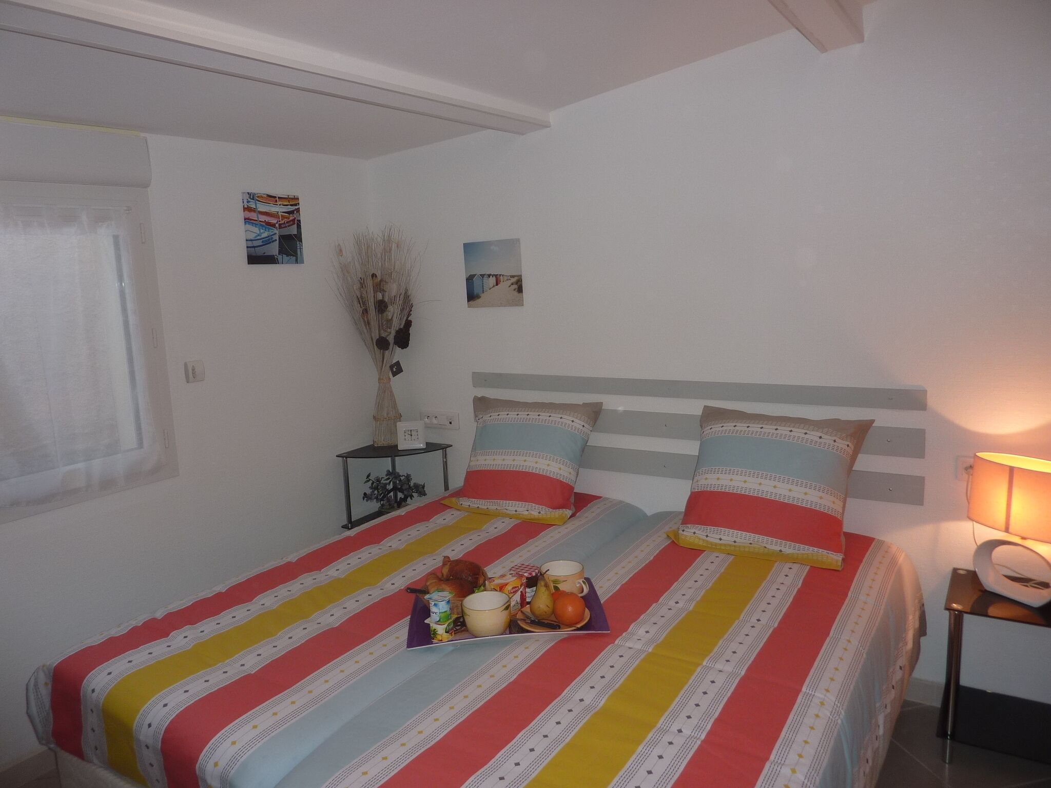 Une chambre avec deux lits, une table de chevet avec une lampe et une fenêtre avec des stores.