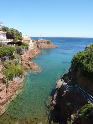 Vista costera con agua cristalina, acantilados rocosos y edificios a lo largo de la orilla.