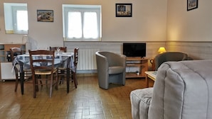 Een eethoek met een tafel, stoelen, een televisie en een bank.