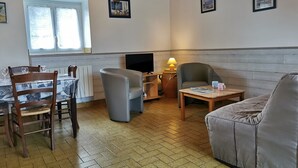 Een gezellige woonkamer met een eettafel, stoelen, een bank en een televisie.