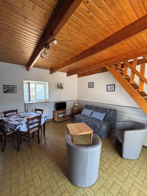Un salon chaleureux avec un plafond en bois, un canapé, une table et un téléviseur.