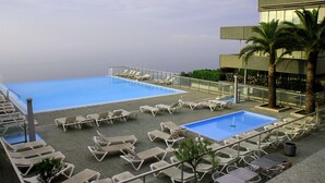 Et tagområde med pool, flere liggestole og en mindre pool.