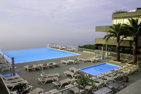 A rooftop pool area with multiple lounge chairs and a small pool.