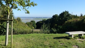 A grassy area with a wooden post, a bench, and a view of the sea. - Very nice apartment, luxury residence, garage, WIFI, 2 free bicycles. (Saint-Valery-Sur-Somme)