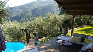 A wooden deck with a pool, outdoor seating, and a view of a mountainous landscape.