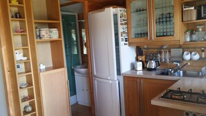 A compact kitchen with wooden cabinets, a white refrigerator, a sink, and a stove.
