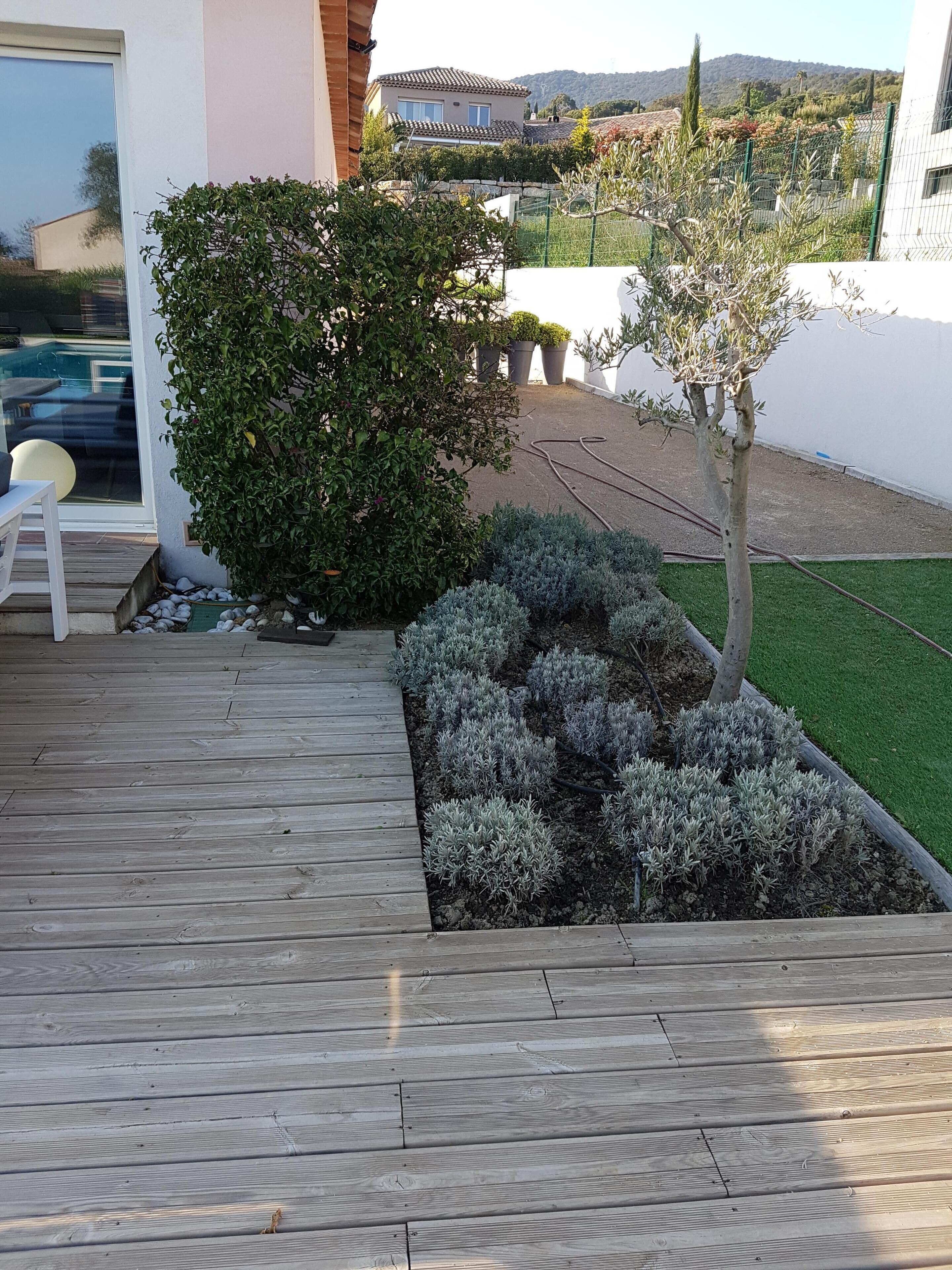 A wooden deck with a small garden area, including a tree and shrubs.