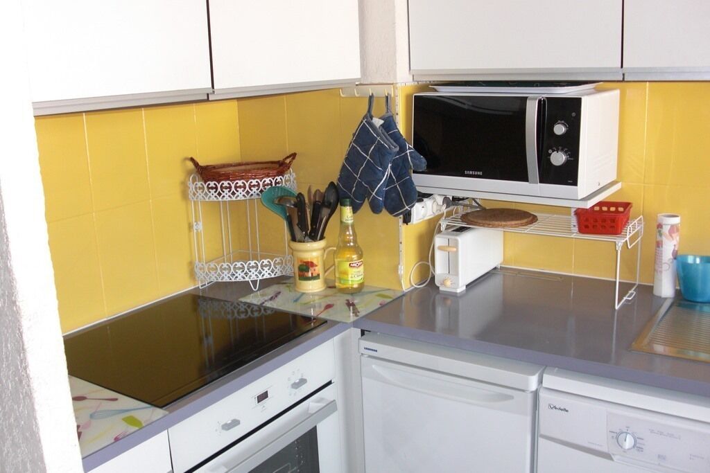 A kitchen with a microwave, oven, and various kitchen utensils.