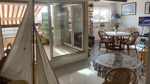 A dining area with a round table, chairs, and a sail-like structure. - Grand Confort two-bedroom apartment with sea view and channel Near Sea (Agde)
