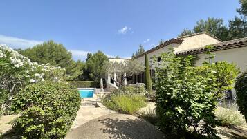 Una villa con piscina, rodeada de abundante vegetación y un cielo azul despejado.