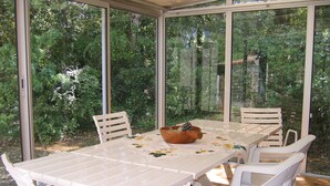 Ein Wintergarten mit Glasdach, einem weißen Tisch und passenden Stühlen.