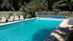 Ein rechteckiger Pool mit klarem, blauem Wasser, umgeben von einem Holzzaun und weißen Liegestühlen.