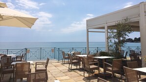 Eine Terrasse im Freien mit Korbmöbeln und Meerblick.