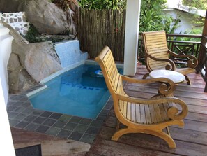 Eine Holzterrasse mit Whirlpool und zwei Holzstühlen.