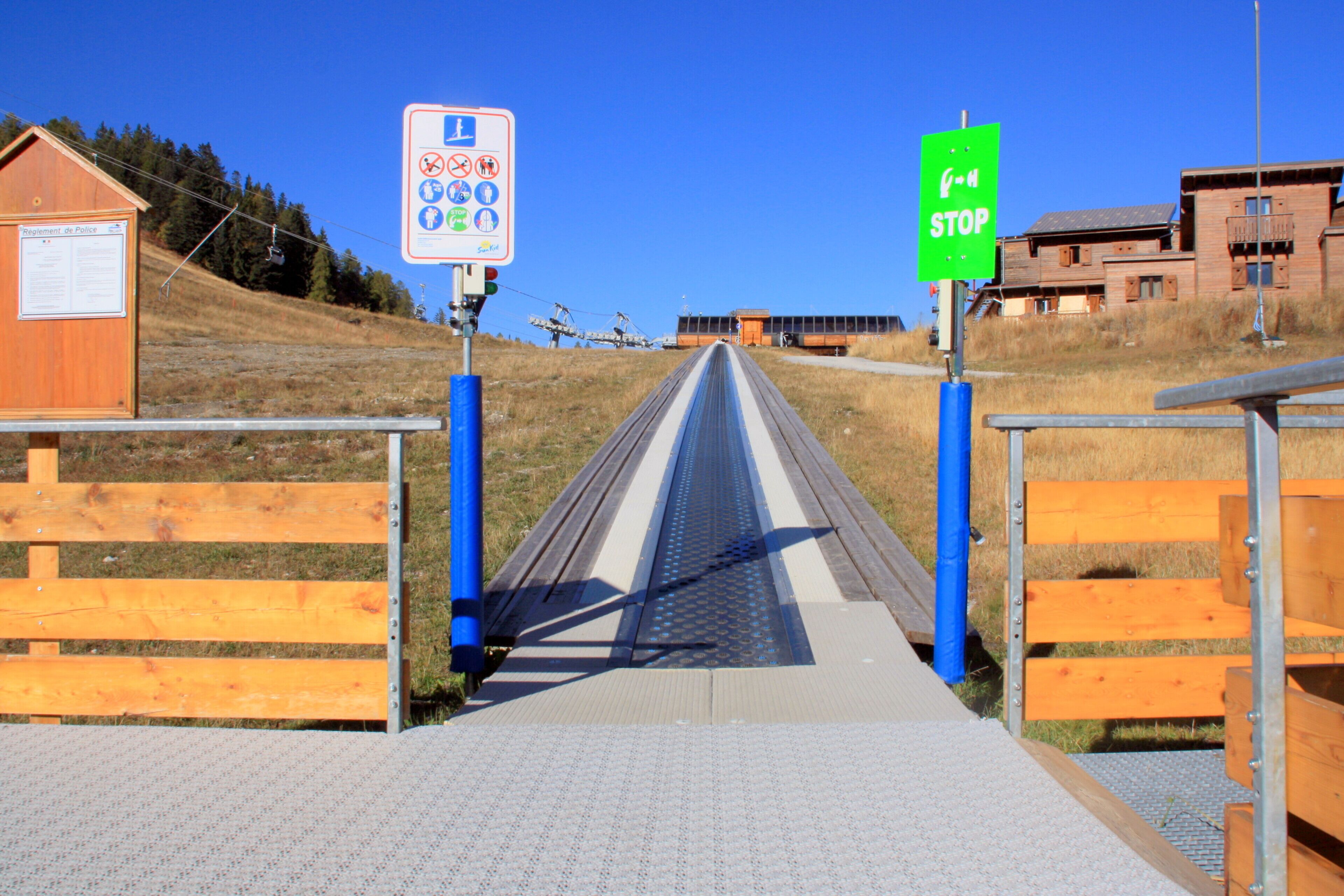 Un chemin menant à un bâtiment où se trouvent un panneau de signalisation et un autre panneau avec des symboles.