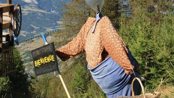 Iemand met een 'BIENVENUE' bord, een kruiwagen en een berg op de achtergrond.